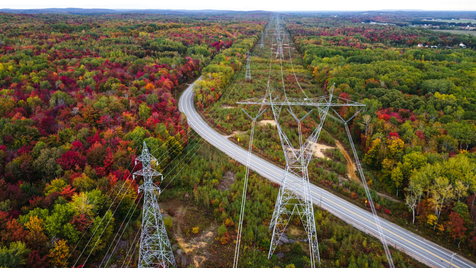 Image showing a large electricity pylon and a road in a forest.